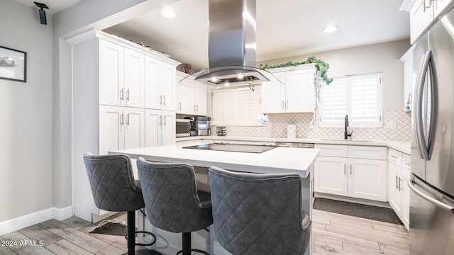 kitchen featuring island exhaust hood, white cabinetry, and sink