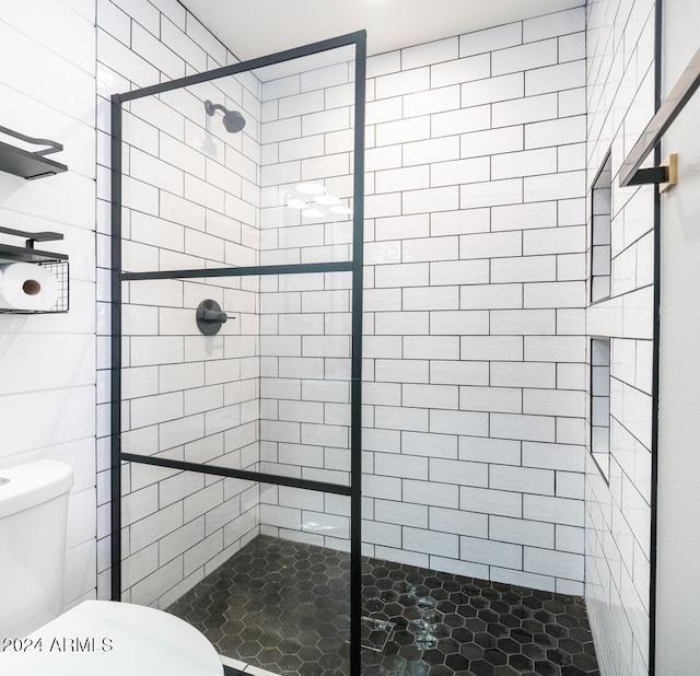 bathroom featuring toilet and a tile shower