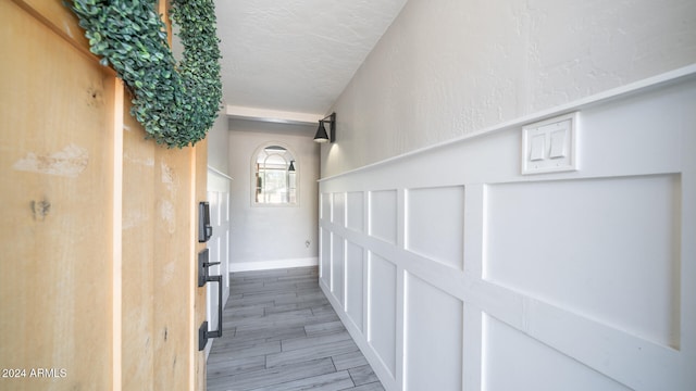 hall with wood-type flooring and a textured ceiling