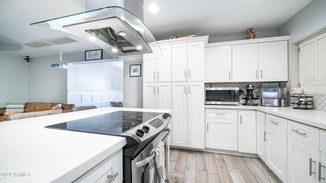 kitchen featuring white cabinets, decorative backsplash, light wood-type flooring, appliances with stainless steel finishes, and island exhaust hood