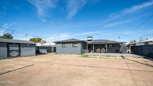 back of property featuring a storage shed, a patio area, and solar panels