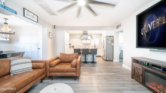 living room with light hardwood / wood-style flooring, a chandelier, and sink