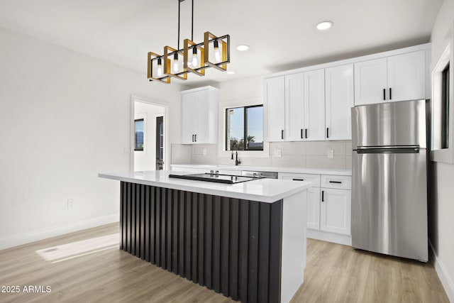 kitchen featuring tasteful backsplash, a kitchen island, white cabinets, and freestanding refrigerator