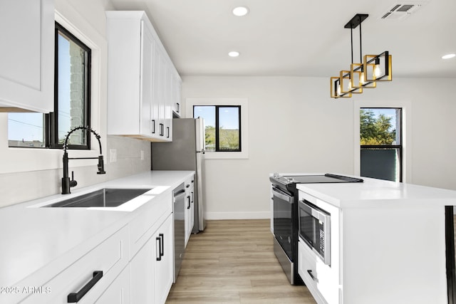 kitchen featuring visible vents, a center island, a sink, a wealth of natural light, and range with electric stovetop