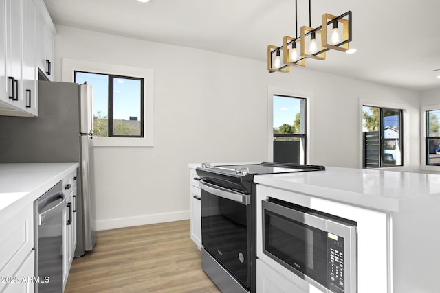 kitchen with a healthy amount of sunlight, light wood-type flooring, appliances with stainless steel finishes, and white cabinets