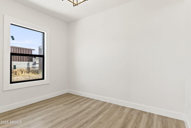 spare room featuring light wood-type flooring and baseboards