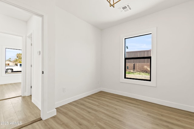 empty room with baseboards, visible vents, and light wood-style floors