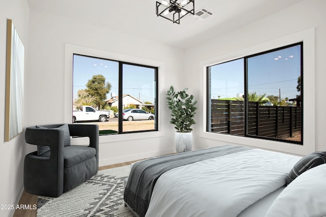 bedroom with baseboards, multiple windows, visible vents, and wood finished floors