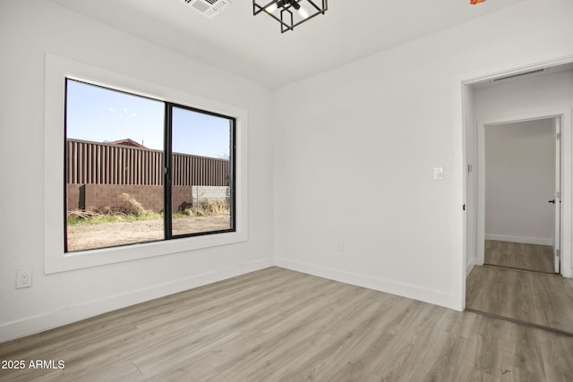 empty room featuring visible vents, baseboards, and wood finished floors