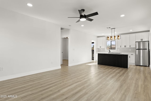 kitchen with white cabinets, a ceiling fan, light wood-style flooring, open floor plan, and freestanding refrigerator