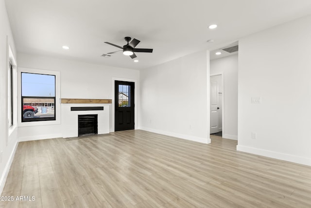 unfurnished living room with light wood-style floors, a fireplace, and a healthy amount of sunlight