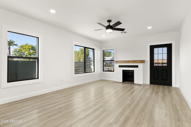 unfurnished living room with visible vents, baseboards, a fireplace with flush hearth, light wood-style flooring, and recessed lighting