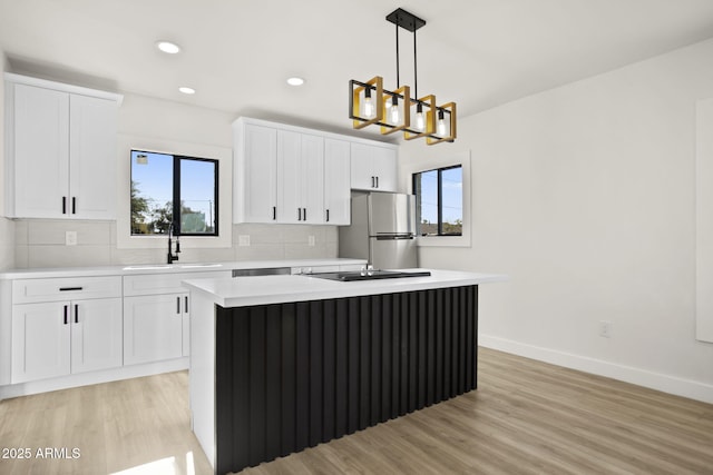 kitchen featuring freestanding refrigerator, a healthy amount of sunlight, a sink, and decorative backsplash