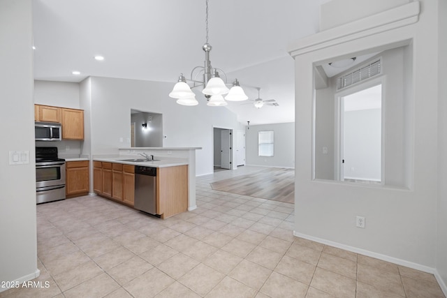 kitchen featuring light countertops, baseboards, ceiling fan with notable chandelier, a peninsula, and stainless steel appliances