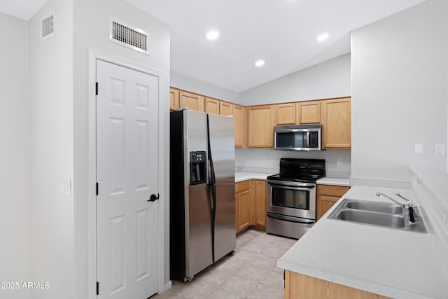 kitchen featuring visible vents, lofted ceiling, a sink, appliances with stainless steel finishes, and light tile patterned floors