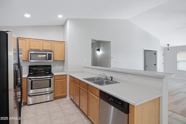 kitchen featuring a sink, appliances with stainless steel finishes, vaulted ceiling, and a peninsula