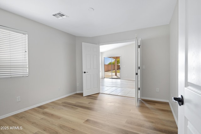 empty room with visible vents, light wood-style floors, and baseboards
