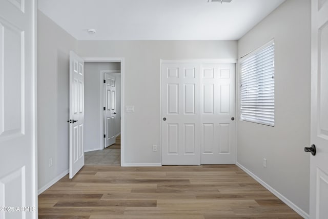 unfurnished bedroom with baseboards, a closet, and light wood-type flooring