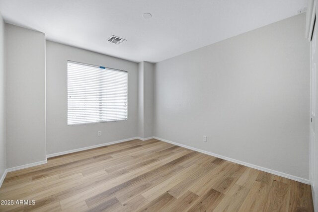 spare room with baseboards, visible vents, and light wood finished floors