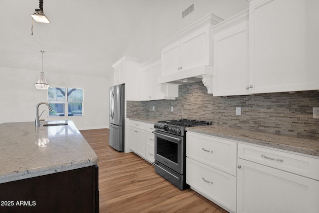 1336 E Belmont Ave, Phoenix, AZ 85020 - kitchen featuring appliances with stainless steel finishes, light wood-style floors, decorative backsplash, and white cabinets