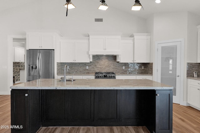1336 E Belmont Ave, Phoenix, AZ 85020 - kitchen featuring stainless steel refrigerator with ice dispenser, stove, white cabinetry, tasteful backsplash, and a large island