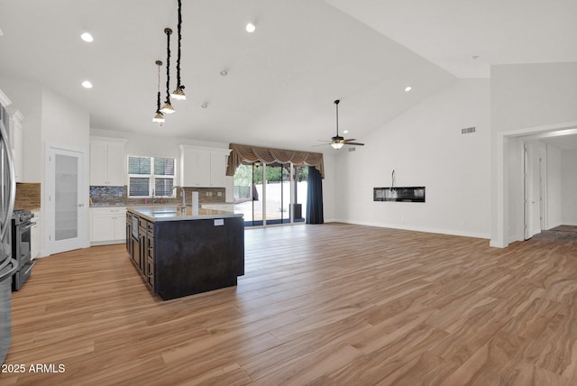 1336 E Belmont Ave, Phoenix, AZ 85020 - kitchen with a center island with sink, ceiling fan, white cabinetry, stainless steel gas range oven, and light wood-style floors