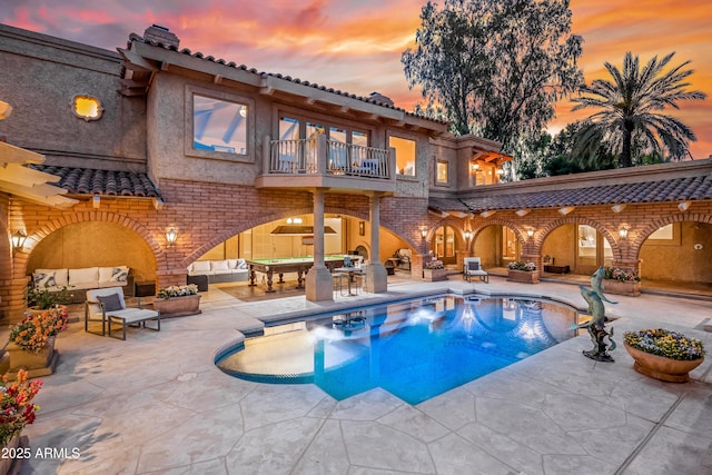 pool at dusk featuring outdoor lounge area and a patio area