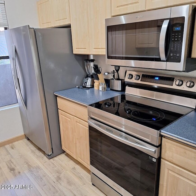 kitchen with stainless steel appliances, light hardwood / wood-style floors, and light brown cabinets