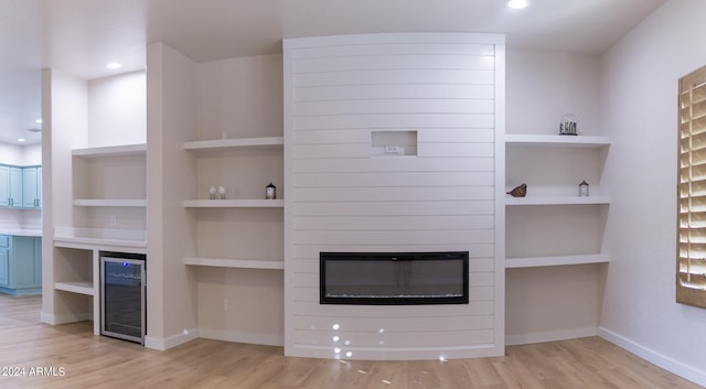 unfurnished living room featuring wine cooler and light hardwood / wood-style floors