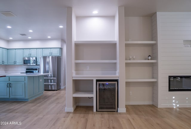 kitchen featuring built in shelves, stainless steel appliances, light hardwood / wood-style flooring, and beverage cooler