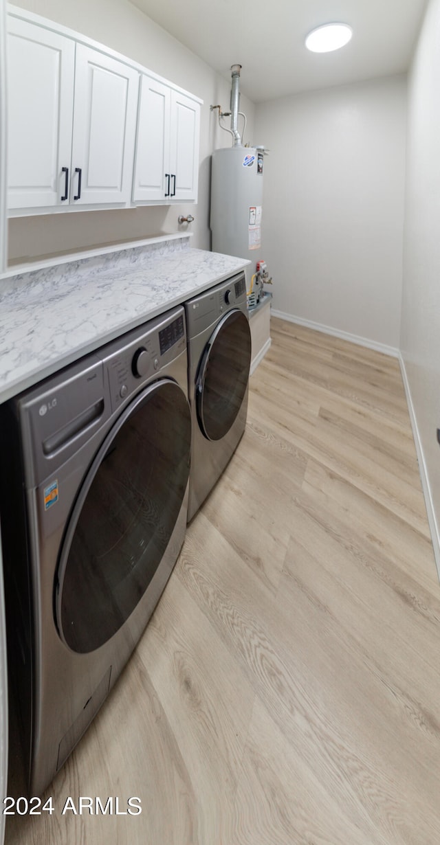 washroom with washer and dryer, water heater, cabinets, and light wood-type flooring