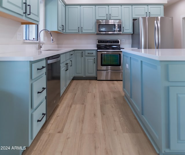 kitchen with stainless steel appliances, sink, and light wood-type flooring