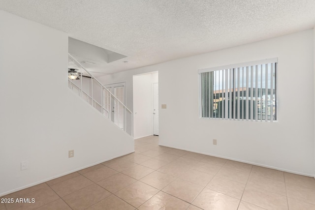 tiled spare room featuring a textured ceiling