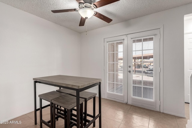 tiled dining area featuring ceiling fan, french doors, and a textured ceiling