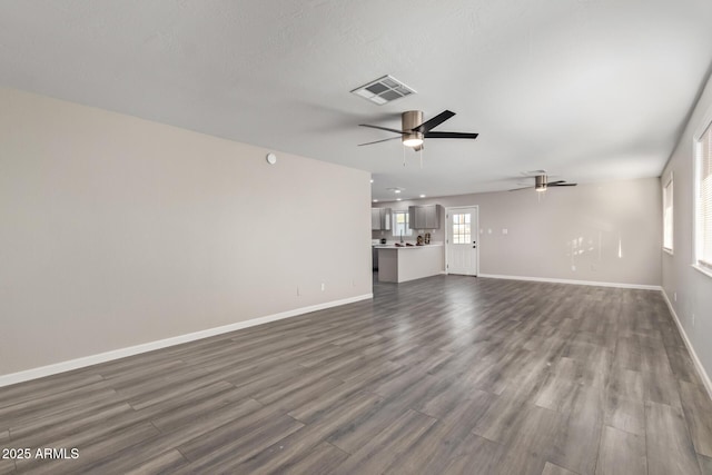 unfurnished living room featuring ceiling fan and dark wood-type flooring