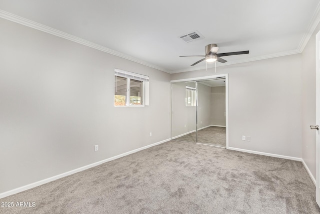 unfurnished bedroom featuring ceiling fan, carpet floors, crown molding, and a closet