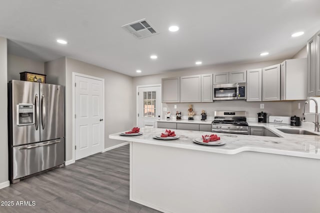 kitchen featuring kitchen peninsula, gray cabinetry, sink, and appliances with stainless steel finishes