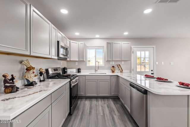 kitchen featuring appliances with stainless steel finishes, sink, hardwood / wood-style flooring, gray cabinets, and plenty of natural light