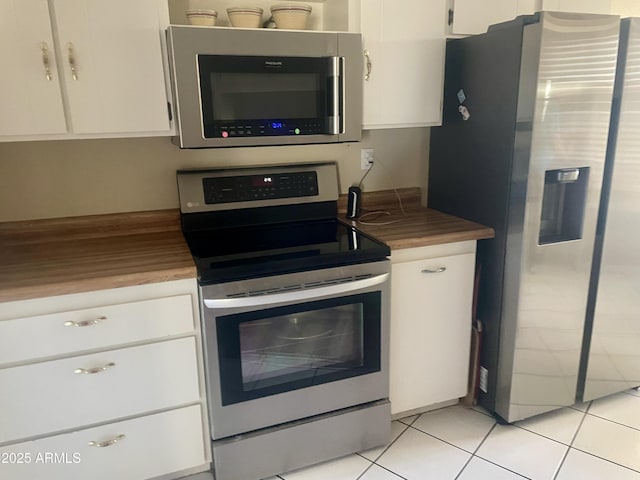 kitchen featuring stainless steel appliances, white cabinetry, light tile patterned floors, and butcher block countertops