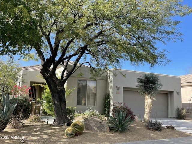 pueblo-style house with a garage, driveway, and stucco siding