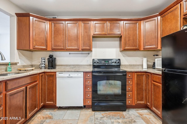 kitchen with light stone counters, sink, and black appliances