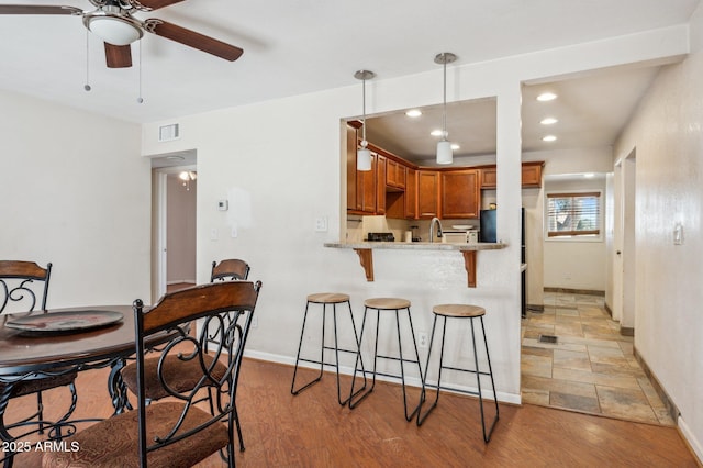 kitchen with a breakfast bar, pendant lighting, sink, kitchen peninsula, and light wood-type flooring