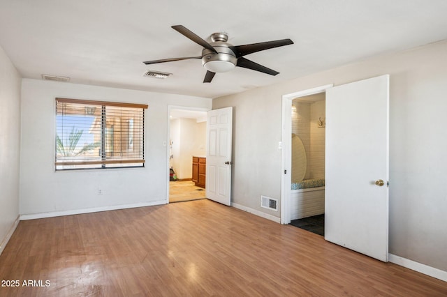 unfurnished bedroom featuring connected bathroom, hardwood / wood-style flooring, and ceiling fan