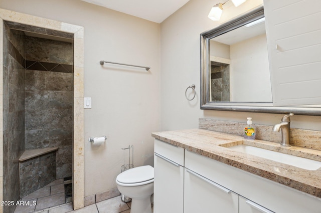 bathroom featuring a tile shower, vanity, tile patterned floors, and toilet