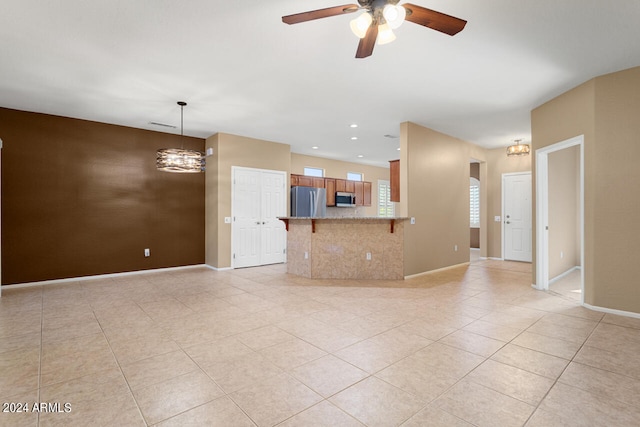 unfurnished living room with ceiling fan with notable chandelier and light tile patterned flooring