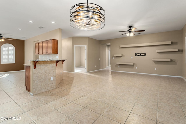 kitchen with light stone counters, ceiling fan with notable chandelier, hanging light fixtures, and light tile patterned floors