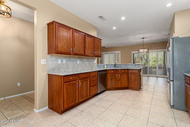 kitchen featuring tasteful backsplash, kitchen peninsula, light stone countertops, pendant lighting, and stainless steel appliances