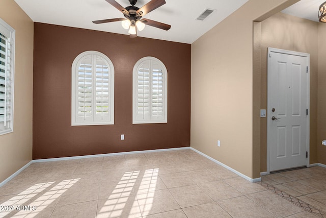 empty room with ceiling fan and light tile patterned floors