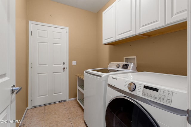 laundry area with washing machine and dryer, light tile patterned flooring, and cabinets