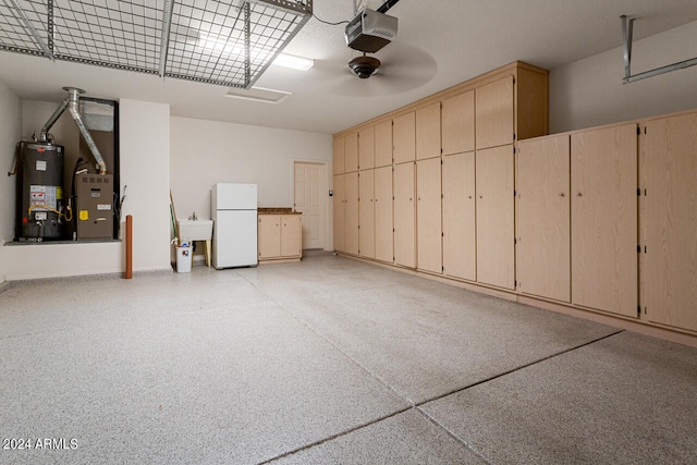 garage featuring a garage door opener, water heater, white fridge, and sink